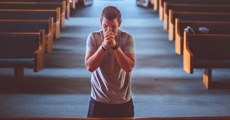 Man kneeling at the altar of a church, mennonite beliefs on salvation