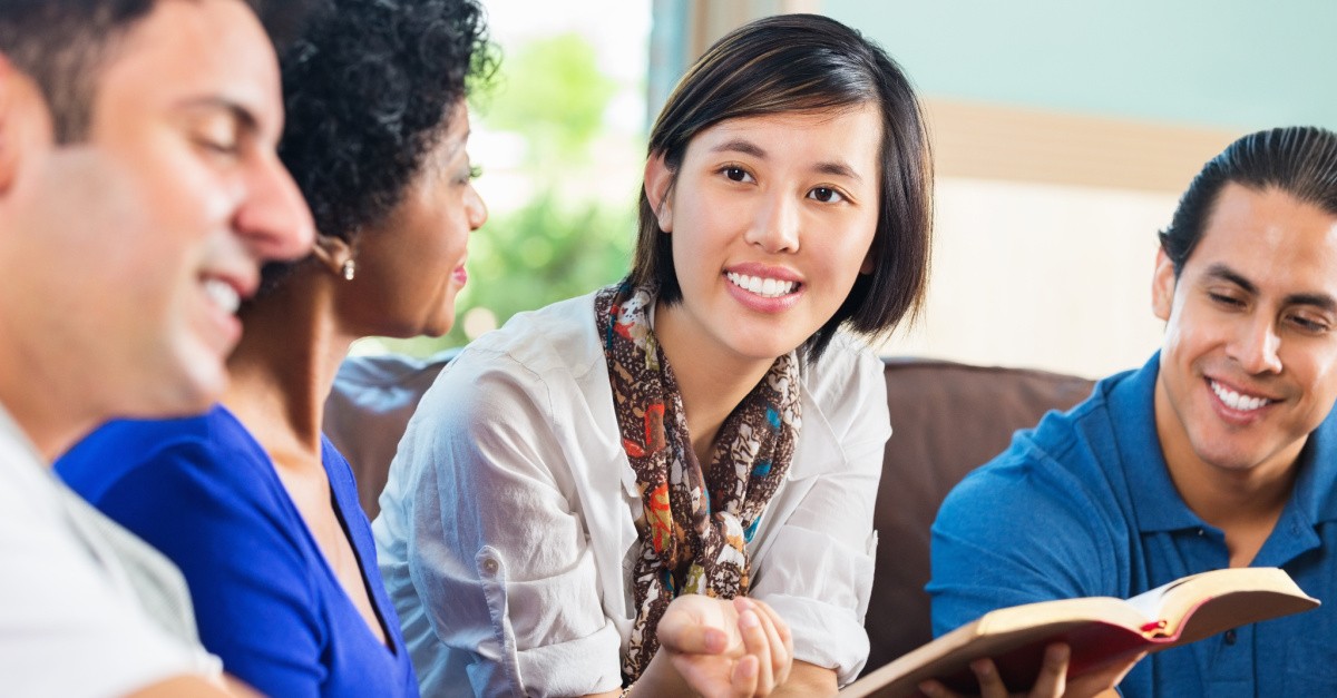 A woman holding a Bible and talking to friends.