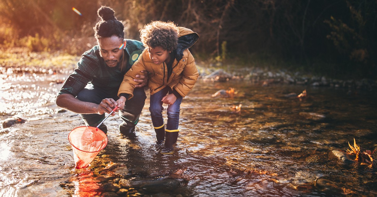 parent Father and son fishing together at creek in the fall