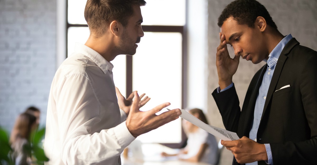 Two men disagreeing at work; persecution is not the same as disobeying policies in place.